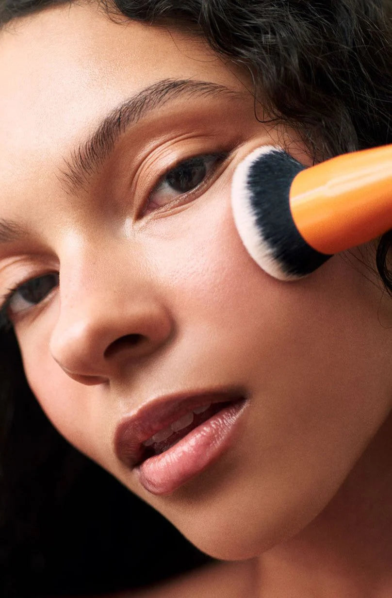 Close-up of a person applying makeup with a brush on their face.